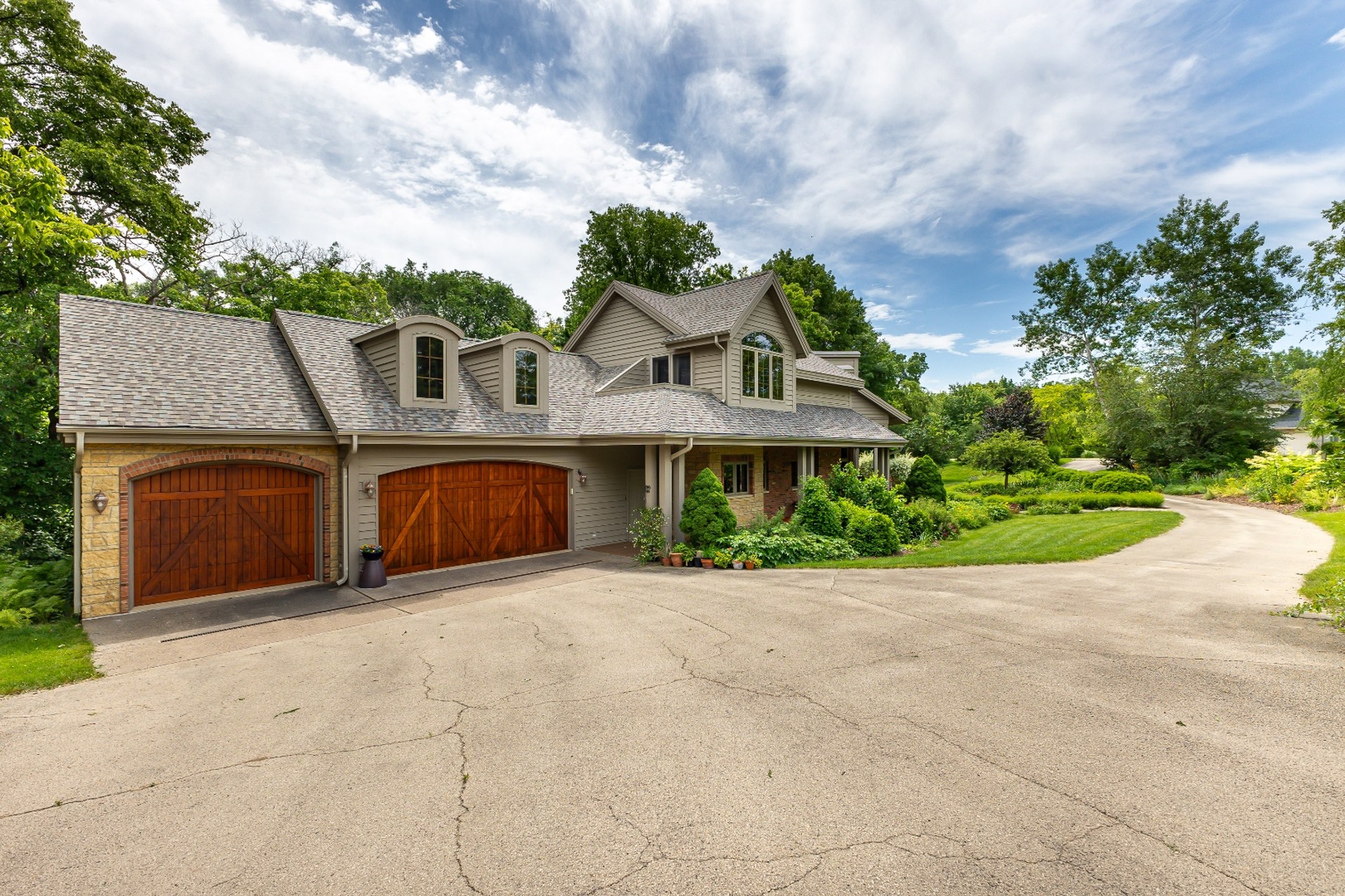 Luxury home exterior with stone facade and wood garage doors in East Dubuque — contact Deb Hooks Real Estate